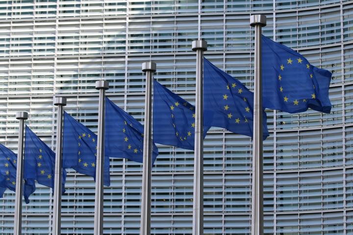 EU flags at the European Commission building in Brussels. Photo via Unsplash.